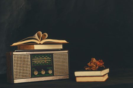Heart-shaped books placed on retro radio receivers with dried flowers on them.